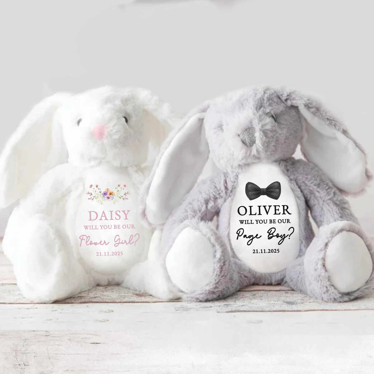 A white bunny and grey bunny soft toys sitting together with a beautiful Flower Girl and Page Boy proposal message