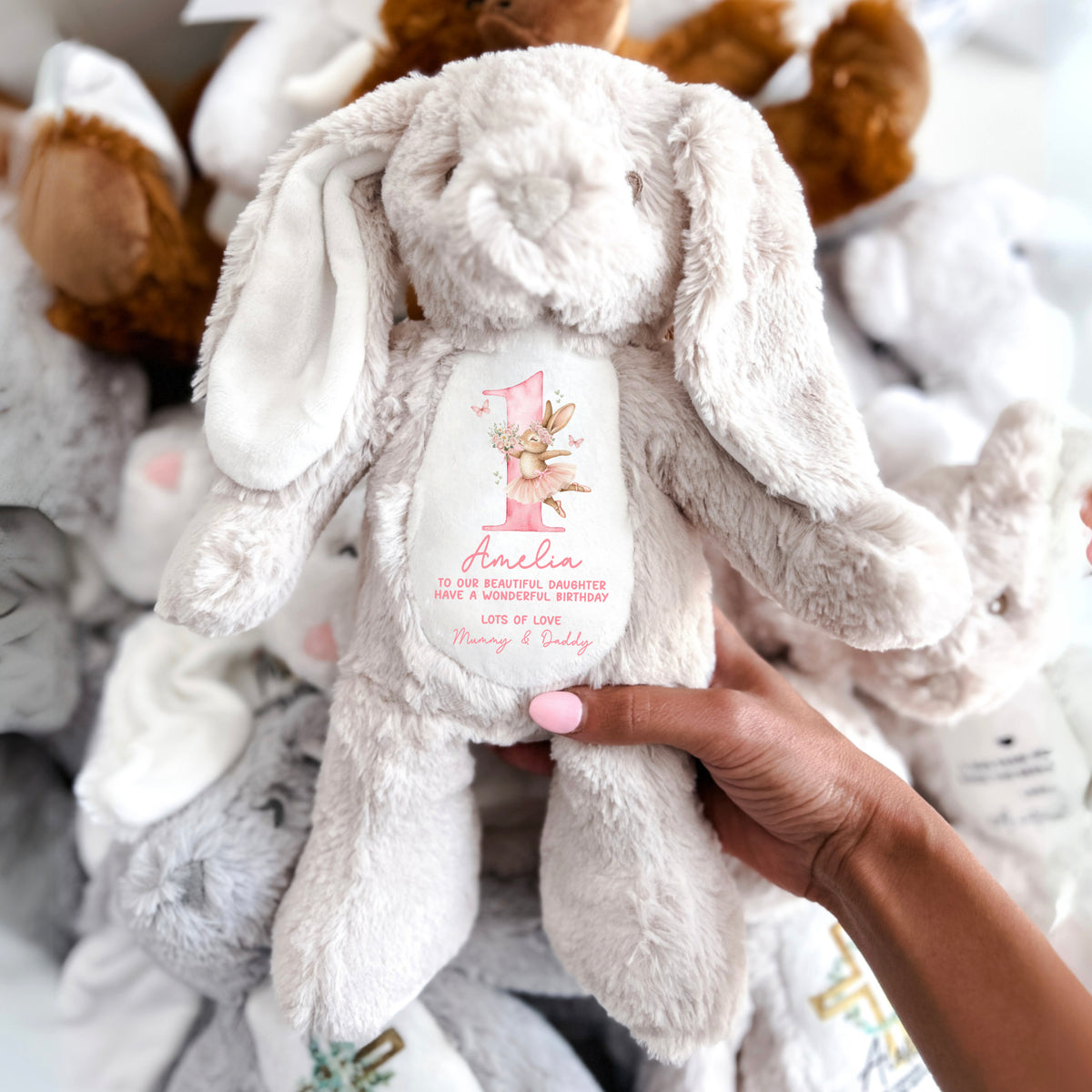 A soft toy brown beige bunny with Happy 1st Birthday message and bunny dressed in a tutu and ballet shoes.