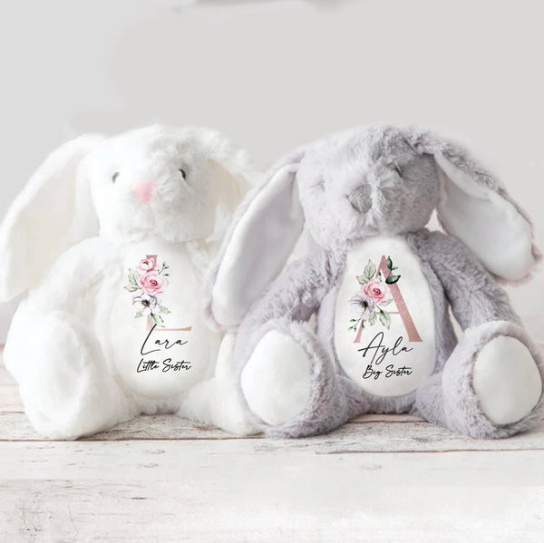 Two soft bunny toys, one white and the other grey, both with floral initials for a Big Sister and Little Sister.