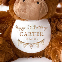 A highland cow soft toy teddy with a Happy Birthday message printed on the white belly, cowboy theme.