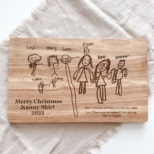 A wooden cheese board with a child's drawing engraved by Ayla & Lara